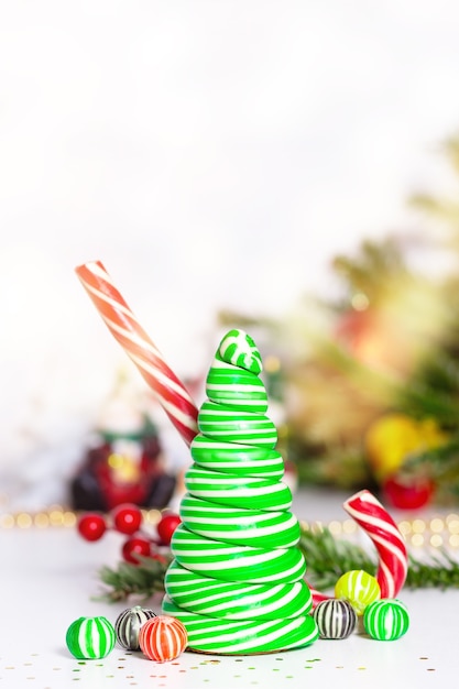 Caramel candy canes christmas tree with fun sweet balls christmas card concept striped christmas caramel tree  light up natural green fir tree with bokeh in background