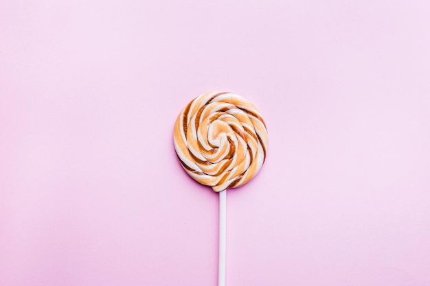 Caramel lollipop on pink background. Flat lay. Minimal concept.