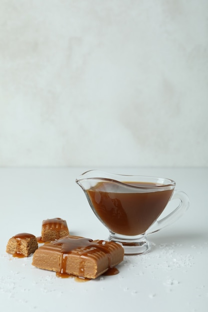 Caramel pieces, sauce and salt on white table