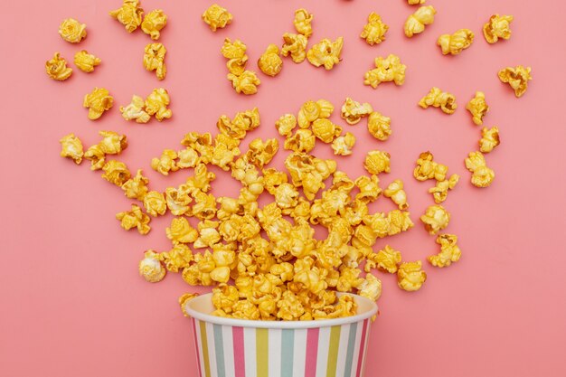 Caramel of pop icons in multicolored cups on pink background