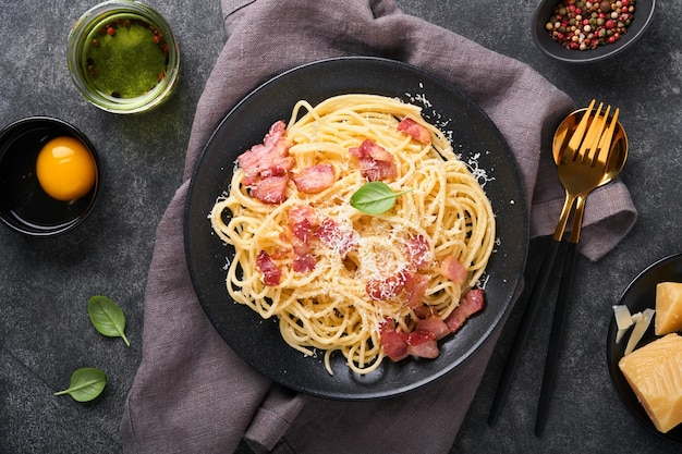 Carbonara pasta Spaghetti with pancetta egg parmesan cheese and cream sauce on old dark black concrete table background Traditional italian cuisine and dish Pasta alla carbonara Top view