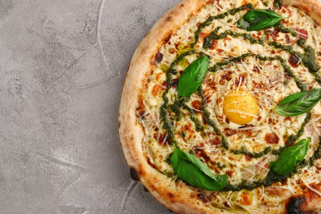 Carbonara pizza with tomatoes, pesto, basil, mozzarella, parmesan, and egg