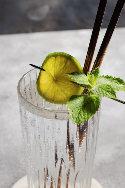 Carbonated mineral water with lime and mint in the glass on gray background