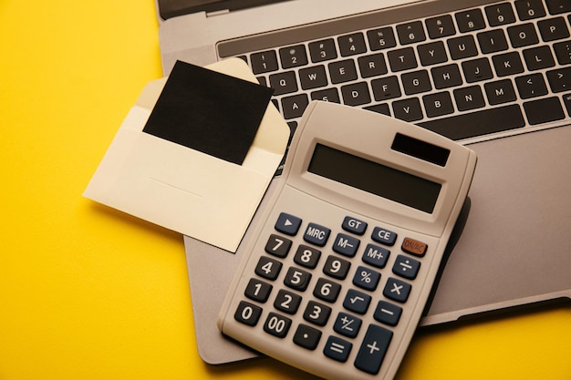 Card in a craft envelope laptop keyboard and calculator on a yellow background