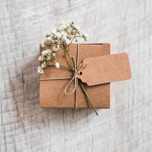 Cardboard box and baby's-breath flower tied with string on wooden backdrop