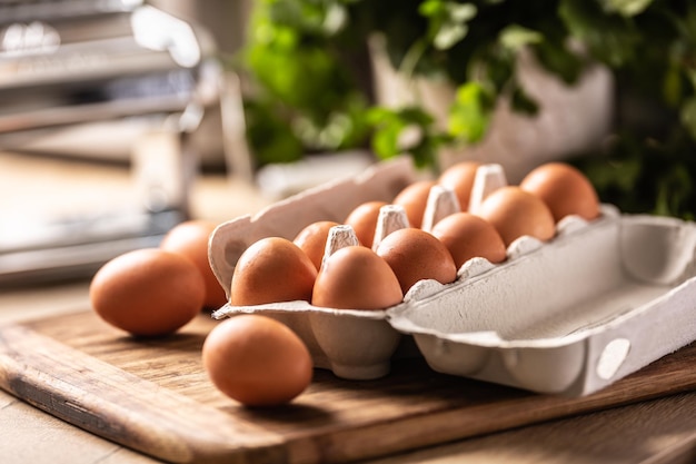 A cardboard box full of fresh chicken eggs on the kitchen counter.