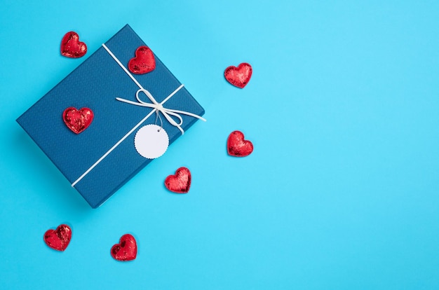 Cardboard box for gifts and red hearts on a blue background top view