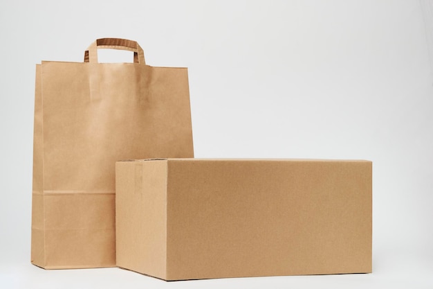 Cardboard box and paper bag on isolated on white background with copy space Delivery and shipping service concept Paper shopping bag and parcel package box closeup