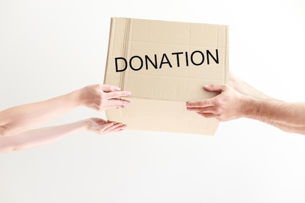 Cardboard box with donations in hands on a white background