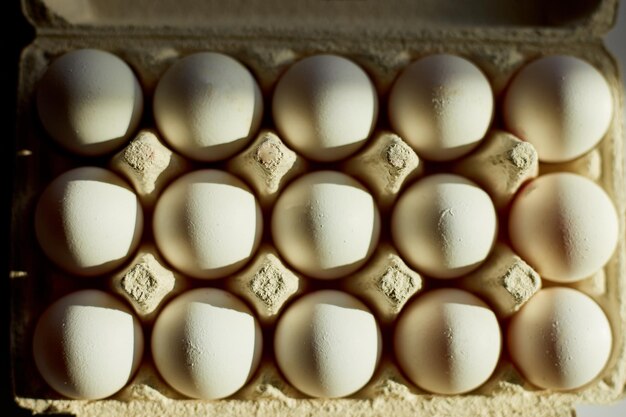 Cardboard box with white eggs on white background