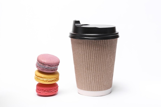 Photo cardboard coffee cup with stack of french macaroons isolated on white background