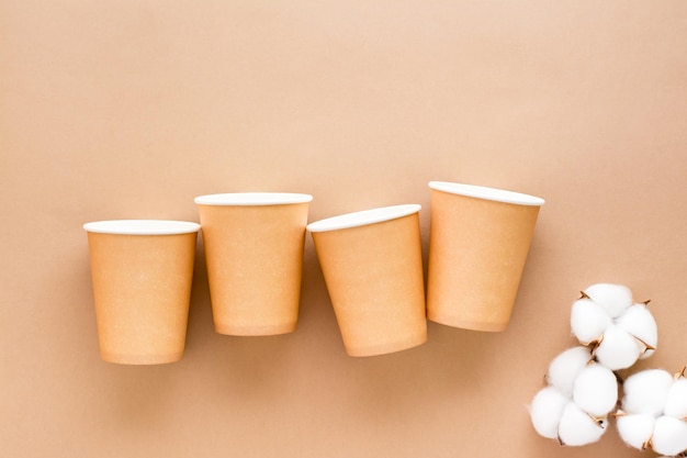 Cardboard cups and cotton buds on a beige background Eco friendly and zero waste concept Top view