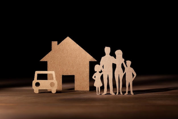 Cardboard family with 2 children next to a house and a car Home and car insurance Family protection