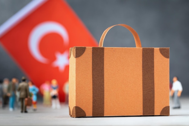 Cardboard suitcase plastic toy people concept on the theme of moving or migration to Turkey