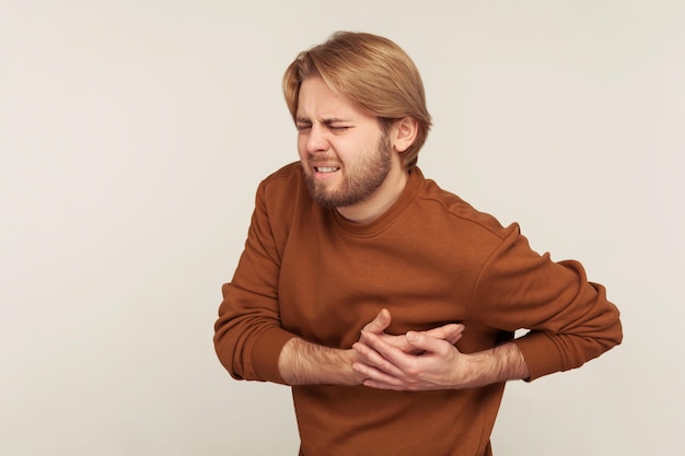 Cardiac health problems Portrait of man in sweatshirt having sudden painful spasm in chest suffering heart attack