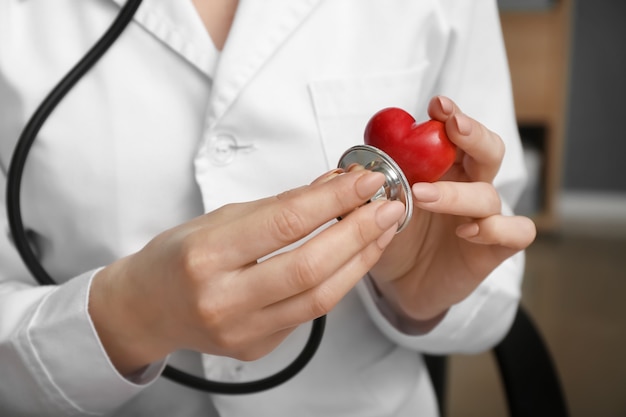 Cardiologist with red heart and stethoscope in clinic