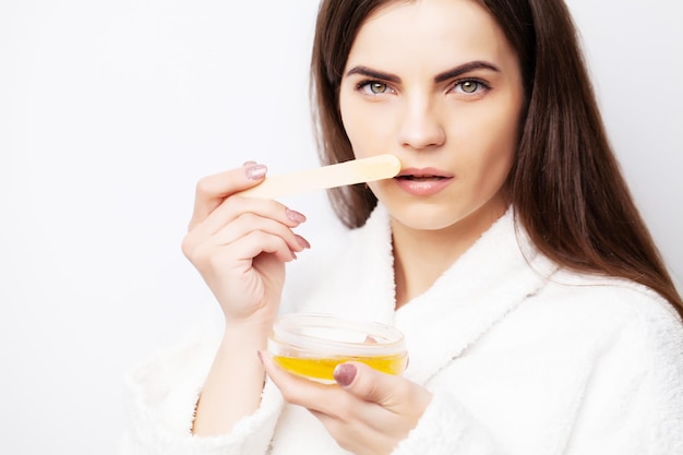 Care concept woman holding bowl with wax for hair removal