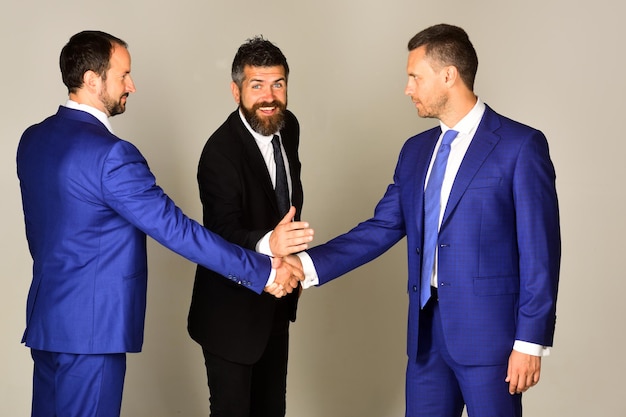 Career and competition concept Businessmen wear smart suits and ties CEOs bet or compete on light grey background Men with beard and smiling faces discuss business or gage