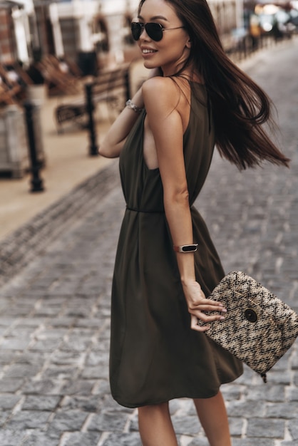 Carefree beauty. Attractive young woman looking over her shoulder and smiling while standing outdoors