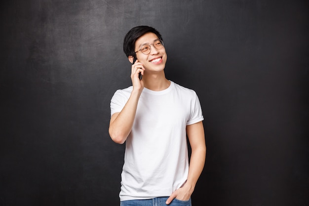 Carefree cheerful asian man talking on phone with friendly attitude