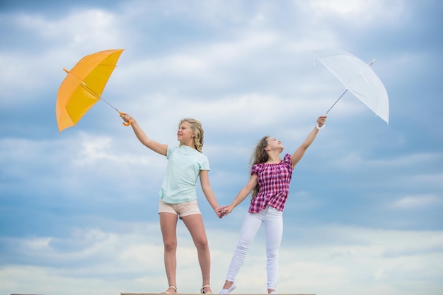 Carefree children outdoors Freedom and freshness Weather forecast Weather changing Girls friends with umbrellas cloudy sky background Ready for any weather Windy or rainy we are prepared