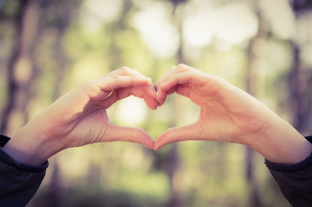 Carefree female hiker framing heart with hands