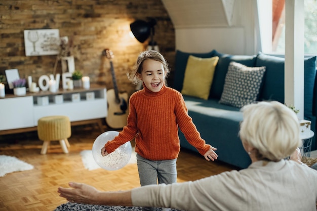 Carefree little girl having fun with her grandmother at home