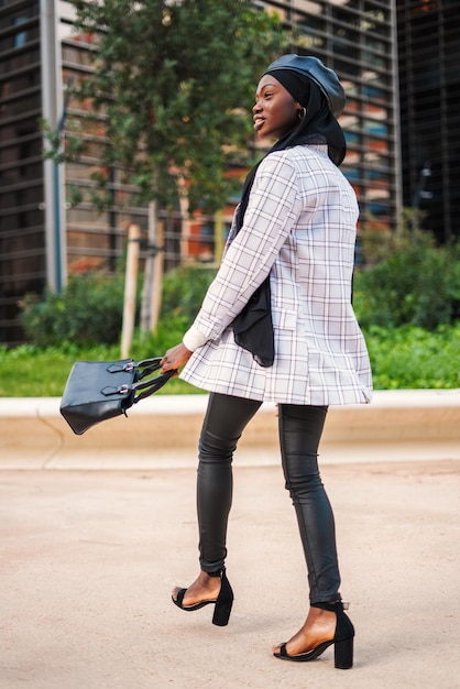 Carefree muslim black woman enjoying walk in city park