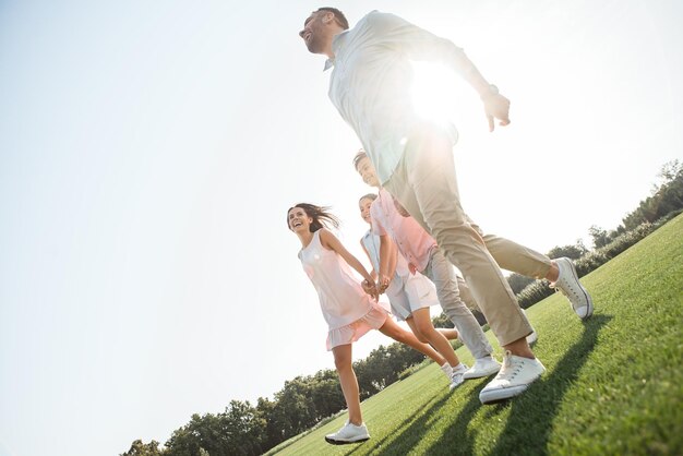 Carefree time together back view of happy and young family of four holding hands smiling