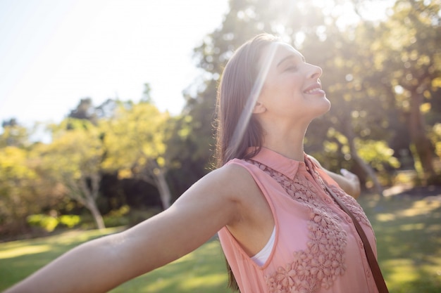 Carefree woman standing with her arms spread in the park