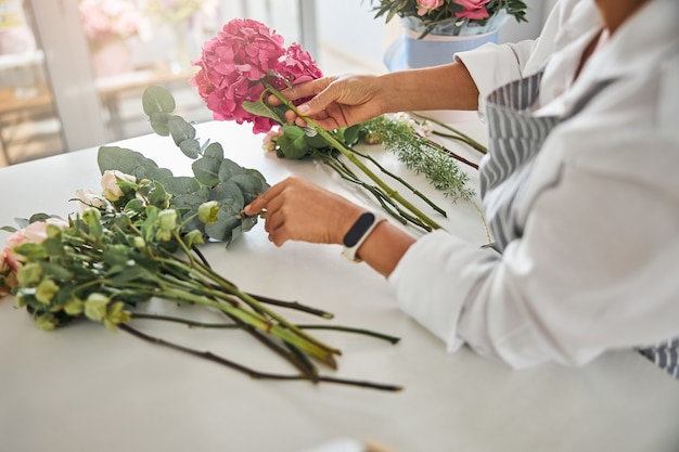 Careful hands of a florist arranging flowers into a composition