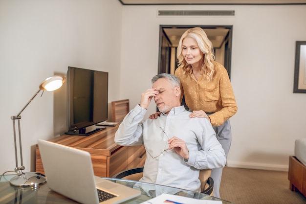 Careful wife. A man working from home and feeling tired, his wife supporting him