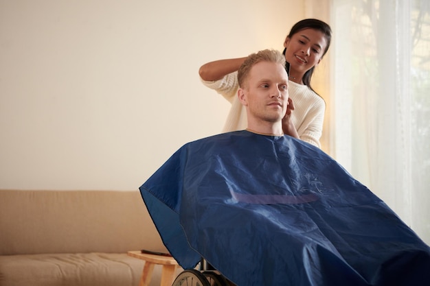 Caregiver Cutting Hair of Young Man