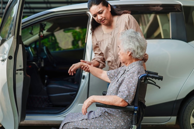 Caregiver help Asian elderly woman disability patient get in her car medical concept