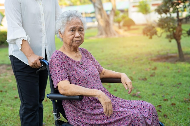 Caregiver help and care Asian elderly woman use walker with strong health while walking at park in happy fresh holiday