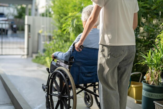 Caregiver help and care Asian senior or elderly old lady woman patient sitting on wheelchair to ramp