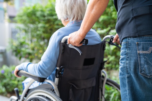 Caregiver help and care Asian senior woman patient sitting on wheelchair to ramp in nursing hospital healthy strong medical concept