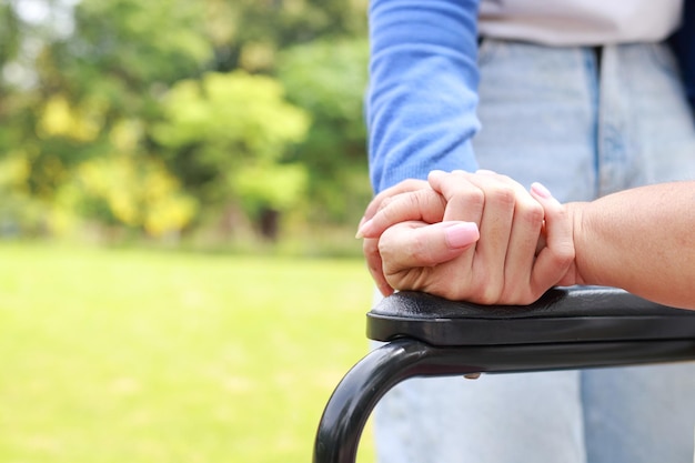 A caregiver shakes hands of an elderly person sitting on a wheelchair Nursing concepts to take care of elderly health care senior health rehabilitation center child taking care of old mother