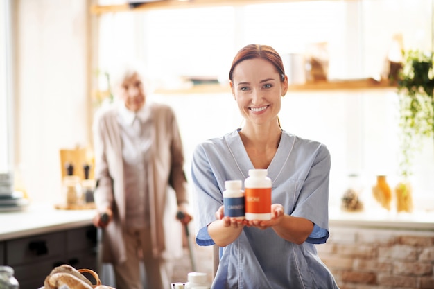 Caregiver wearing uniform holding packs of medication