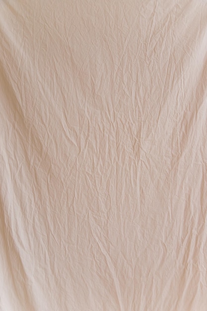 Carelessly crumpled beige fabric as a background image Uneven surface The texture of the cotton fabric