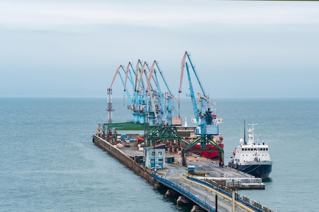 Cargo berth with port cranes and moored ships against the backdrop of the open sea