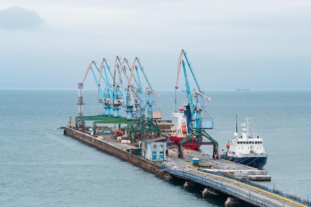 Cargo berth with port cranes and moored ships against the backdrop of the open sea