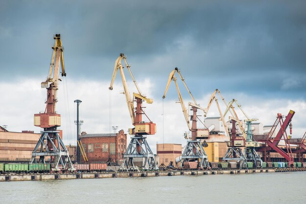 Photo cargo cranes and railway cars in the port under the stormy sky