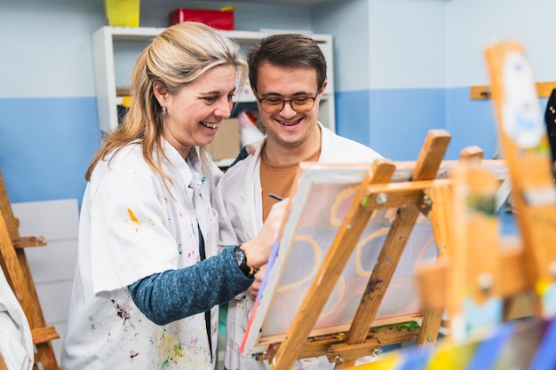 Photo caring art teacher guides her student with down syndrome