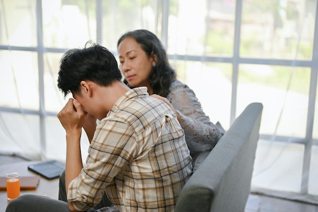 A caring Asian mom is trying to comfort and support her crying and sad son care family support