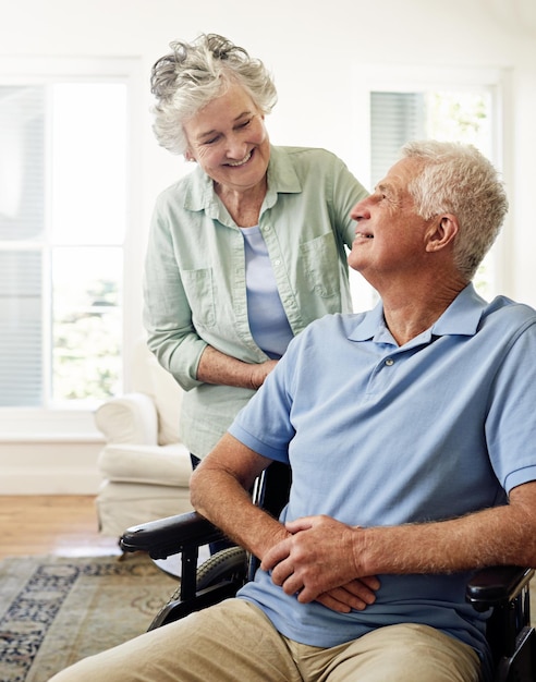 Caring for each other in their winter years Shot of a smiling senior man in a wheelchair and his wife at home