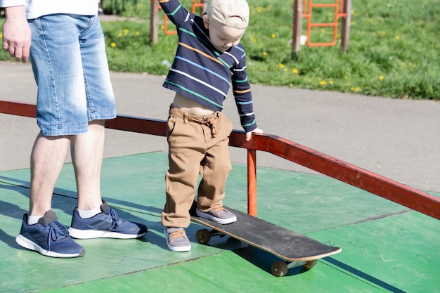 A caring and loving father teaches his threeyearold son to skateboard