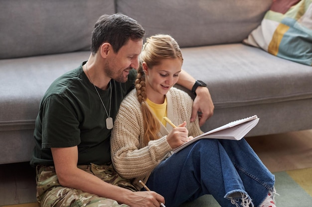 Caring military father helping daughter doing homework