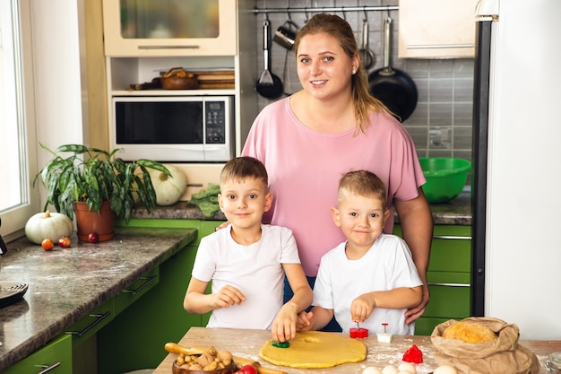 Caring mother help little preschooler sons prepare cookies, smiling loving mom learn cooking with small boys child, making lunch on weekend in kitchen together