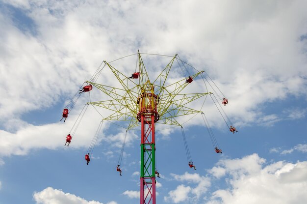 A carousel with people on a high tower against the sky.